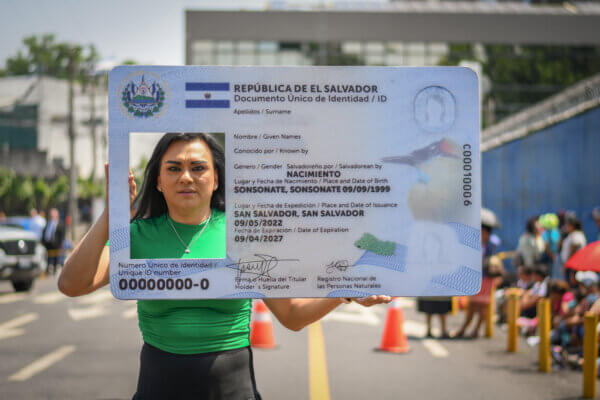 Mónica Linares, directora de la asociación ASPIDH, sostiene una tarjeta de identidad gigante en una manifestación por el derecho al cambio de nombre en El Salvador.